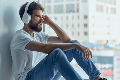 Young man looking away while sitting outdoors