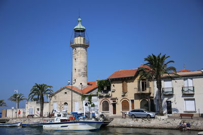 Lighthouse by sea against clear sky