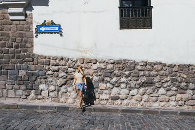 A young woman is standing near a white wall in cusco, peru