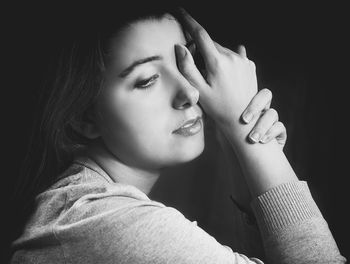 Close-up portrait of young woman against black background