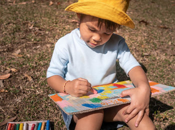 Girl sitting while painting with crayons while sitting on land