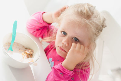 High angle portrait of sad girl sitting with breakfast cereal at table