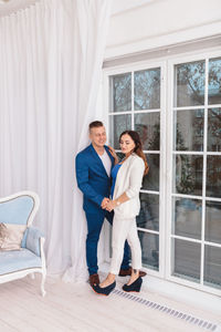 Couple standing against window at home