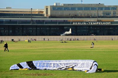 People playing soccer on field against buildings