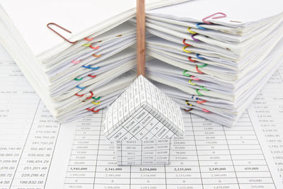 High angle view of papers stacked by model home on table