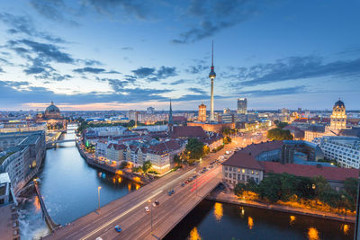 Bridge in illuminated city during sunset