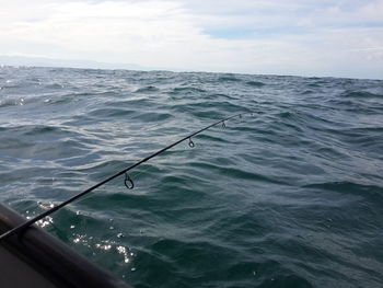 Fishing rod over sea against sky
