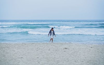 Woman standing at beach against sky