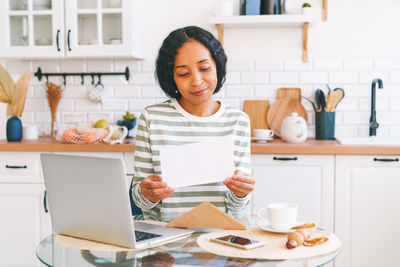 Young african-american female opening and reading paper letter. concept of receiving correspondence