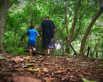 Rear view of two people standing in forest