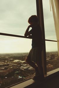 Boy standing by sea against sky