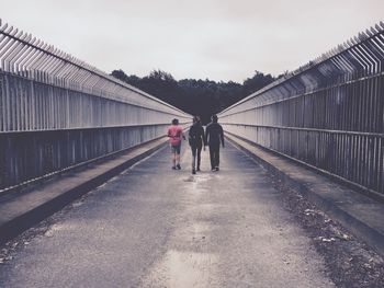 Rear view of people walking on road against sky