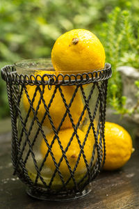 Close-up of lemons in container on wooden table