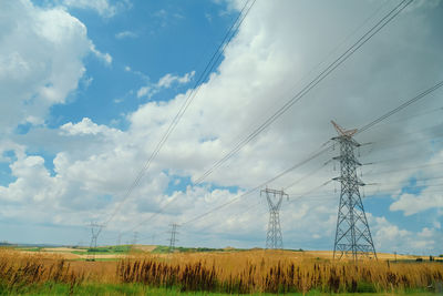 Low angle view of electricity pylon on field against sky