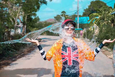 Water splashing on young woman standing on road