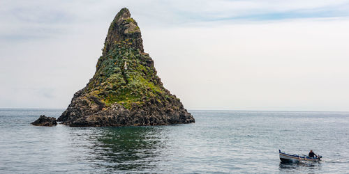 Rock formation in sea against sky