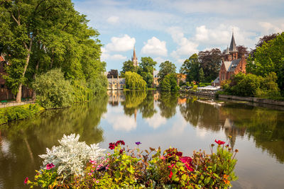 View to minnewaterpark at bruges, belgium - lake surrounded by trees, flowers and old buildings