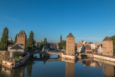 Bridge over river amidst buildings against blue sky