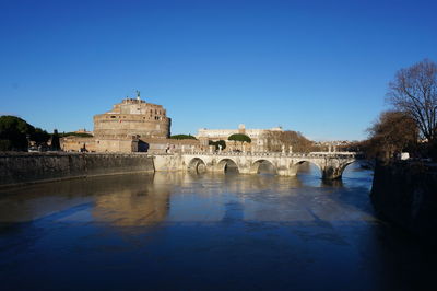 Arch bridge over river against clear blue sky