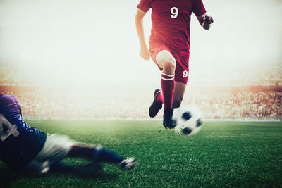 Low section of players playing with soccer ball on field