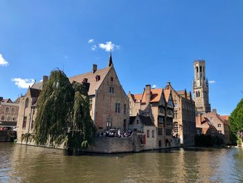 River amidst buildings in city against blue sky