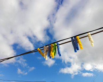 Low angle view of clothespins hanging on against sky