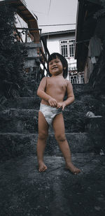 Portrait of young woman standing against building