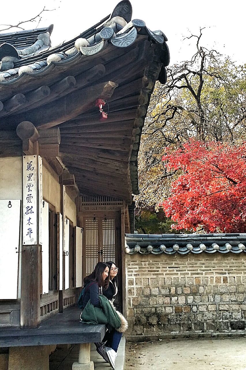 lifestyles, leisure activity, person, built structure, standing, casual clothing, architecture, tree, building exterior, clear sky, day, men, rear view, outdoors, sitting, full length, young adult, traditional clothing