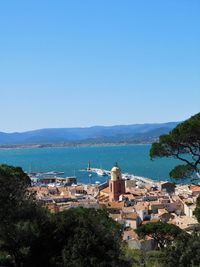 High angle view of buildings and sea against clear blue sky