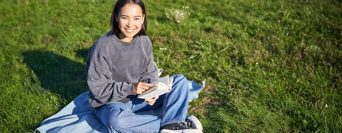 Portrait of young woman sitting on field