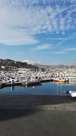 Boats moored at harbor against sky