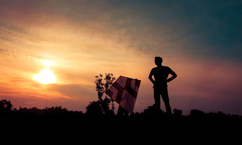 Silhouette man standing on field against sky during sunset