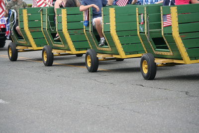 People sitting in vehicle trailer on street during independence day parade