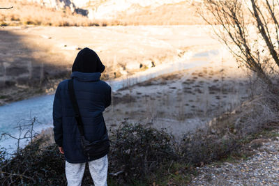 Unrecognizable teenager wearing hoodie and jacket looking the sunset