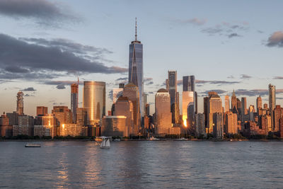 Sea by modern buildings against sky in city