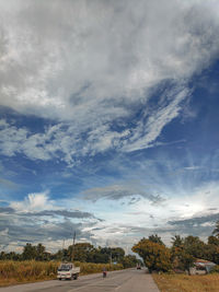 Road by trees against sky