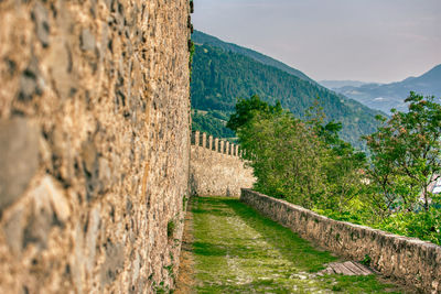 Stone wall of building and mountains against sky