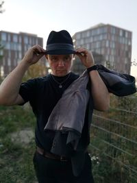 Portrait of man wearing hat with buildings in background