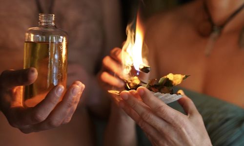 Midsection of people holding burning candles