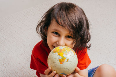 High angle portrait of cute boy holding globe