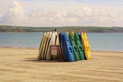 Deck chairs on beach against sky