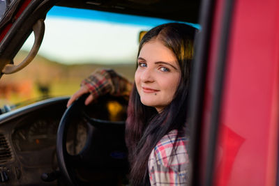 Portrait of young woman in red car