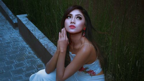 Beautiful young woman sitting on sidewalk