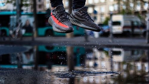 Low section of man jumping in puddle