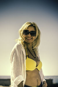 Portrait of woman wearing sunglasses standing against sky