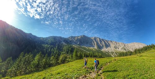 Rear view of man walking on mountain against sky