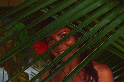 Close-up portrait of smiling woman by palm leaves