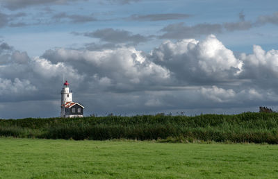 Lighthouse on field against sky