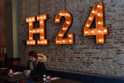 Full length of woman with text on table in cafe