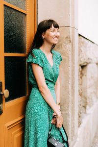 Young woman smiling while standing against wall